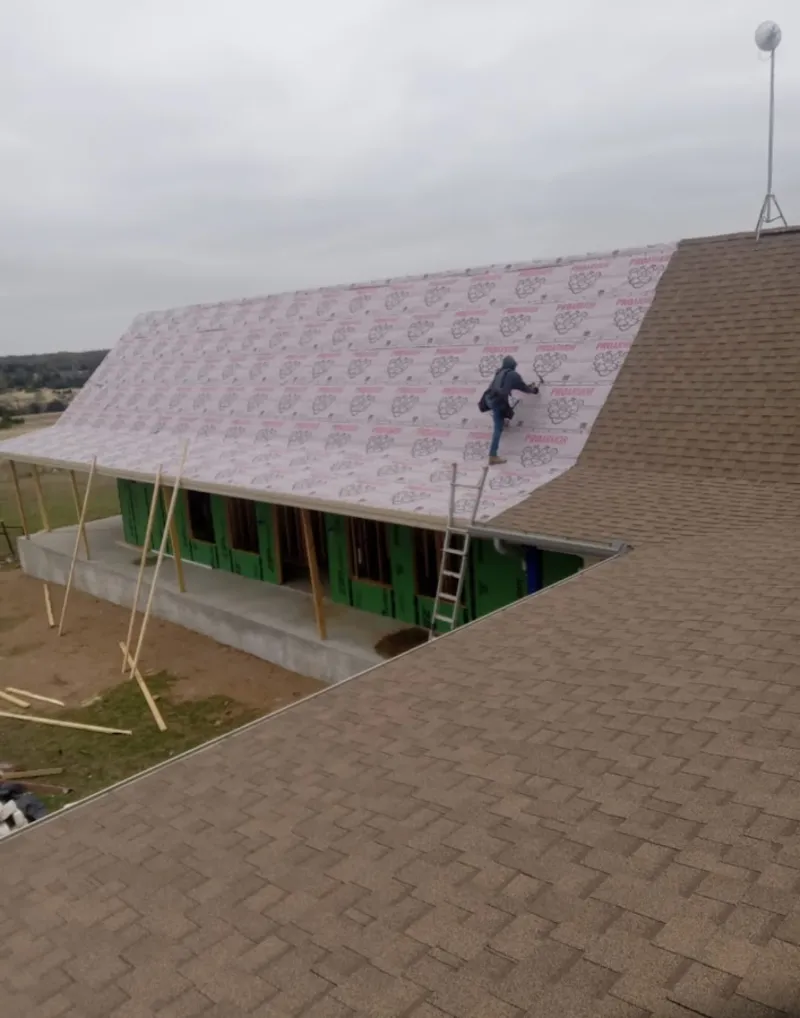 Worker preparing underlayment for a metal roof installation in Pine Ridge